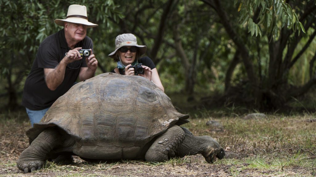 Photo of two travelers with a huge Galapagos tortoise